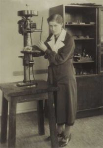 Nainen seisoo kellosepän työkalun vieressä