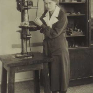 Nainen seisoo kellosepän työkalun vieressä
